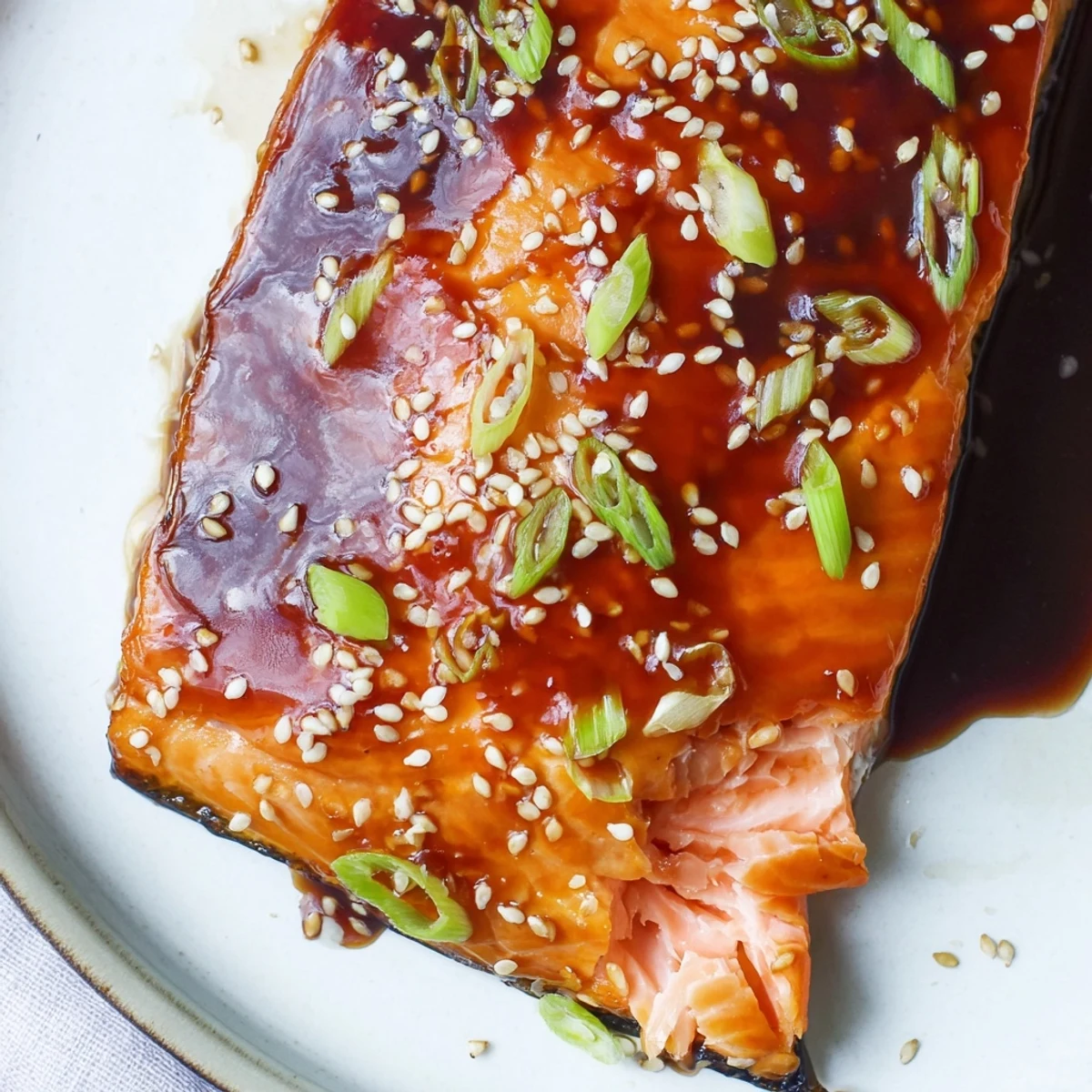 Glistening gluten free teriyaki salmon fillets brushed with a thick, sticky sauce on a parchment-lined baking sheet