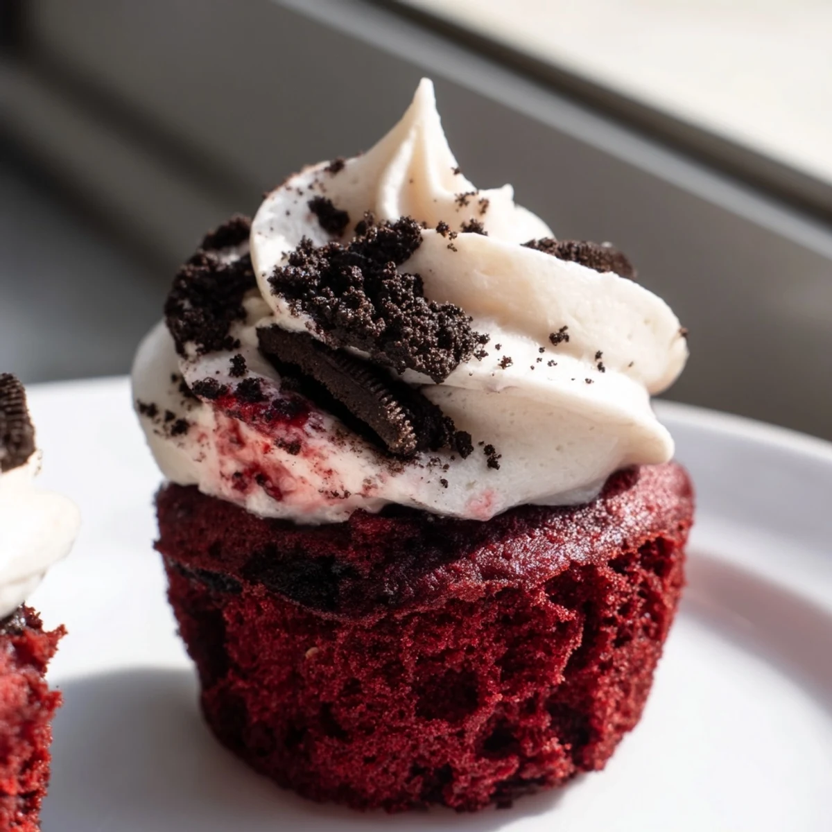 Red Velvet Oreo Cupcakes topped with creamy cookie frosting on a rustic plate