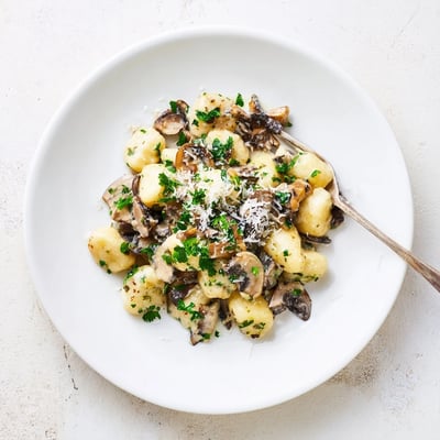 A close-up of Creamy Mushroom Gnocchi in a shallow bowl, highlighting golden mushrooms and melted Parmesan for a cozy dinner.