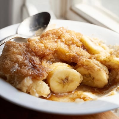 Warm Southern banana cobbler served with vanilla ice cream in a rustic dish