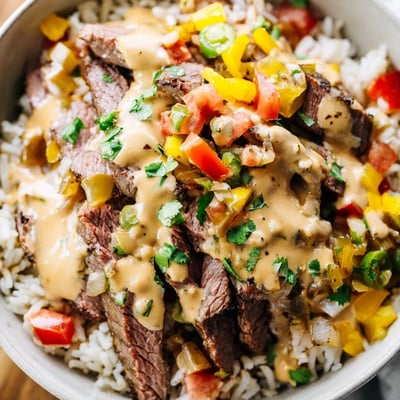 Sizzling steak queso rice in a cast iron skillet with colorful bell peppers